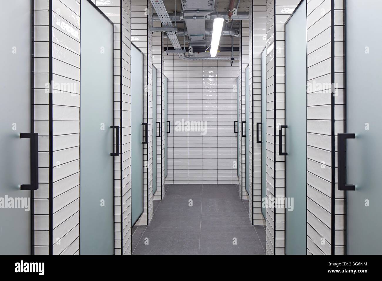Corridor in washroom with tiled walls. 66 Shoe Lane, London, United Kingdom. Architect: Stiff + Trevillion Architects, 2020. Stock Photo