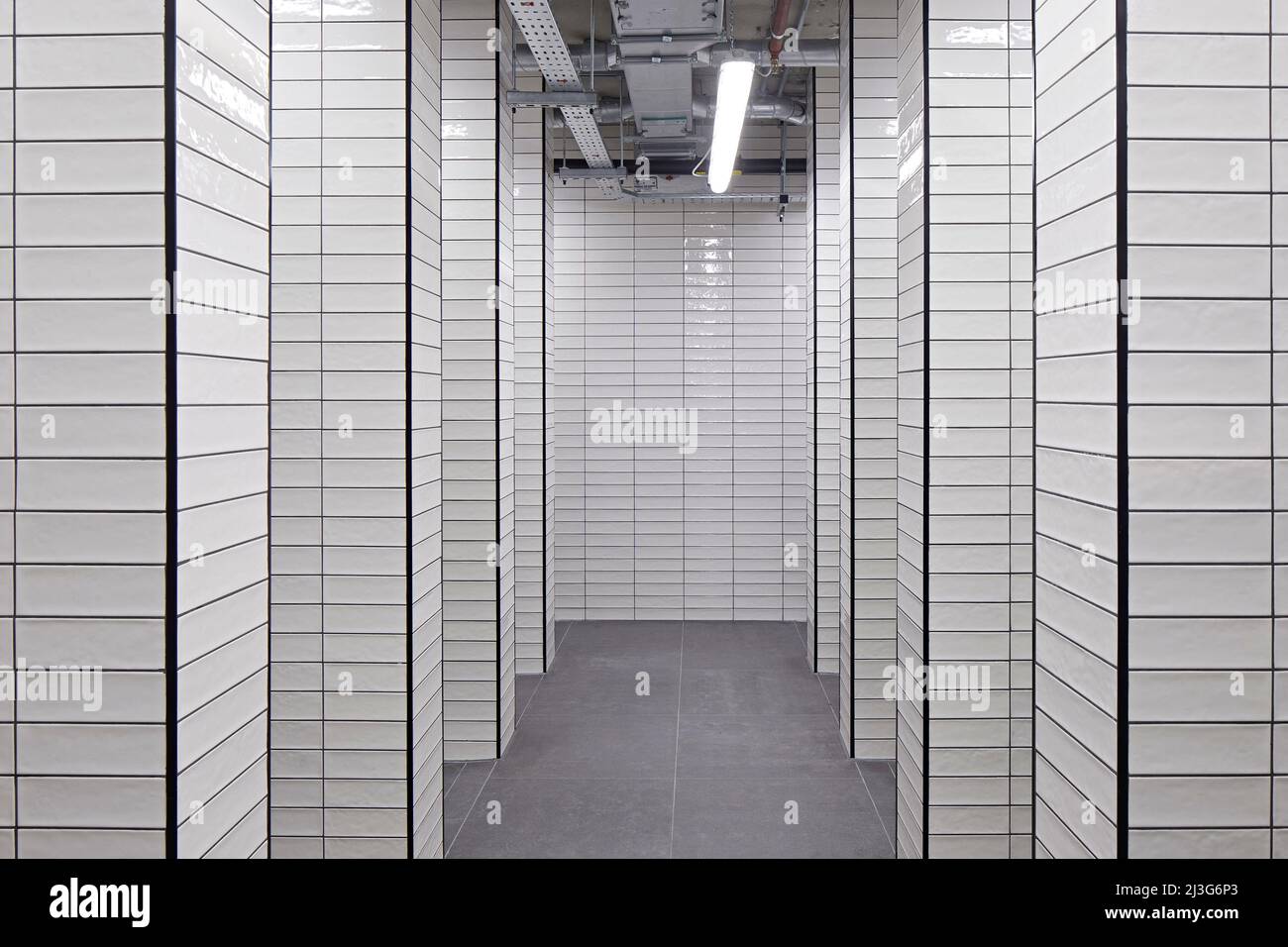 Corridor in washroom with tiled walls. 66 Shoe Lane, London, United Kingdom. Architect: Stiff + Trevillion Architects, 2020. Stock Photo