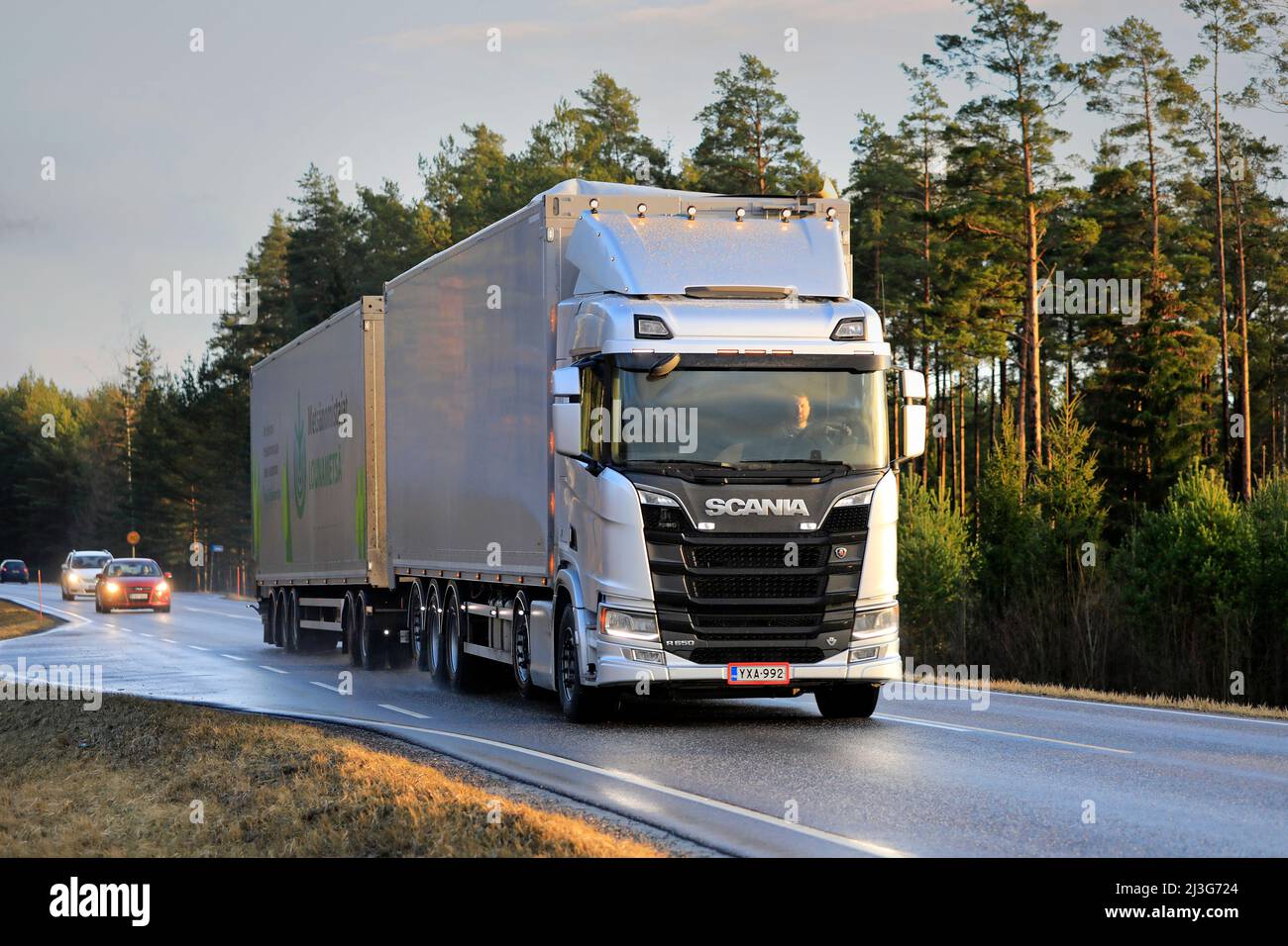 Silver Scania R650 truck pulls hopper trailer for peat transport on Road 52 at sunset time in winter. Long transport. Salo, Finland. Feb 21, 2020. Stock Photo