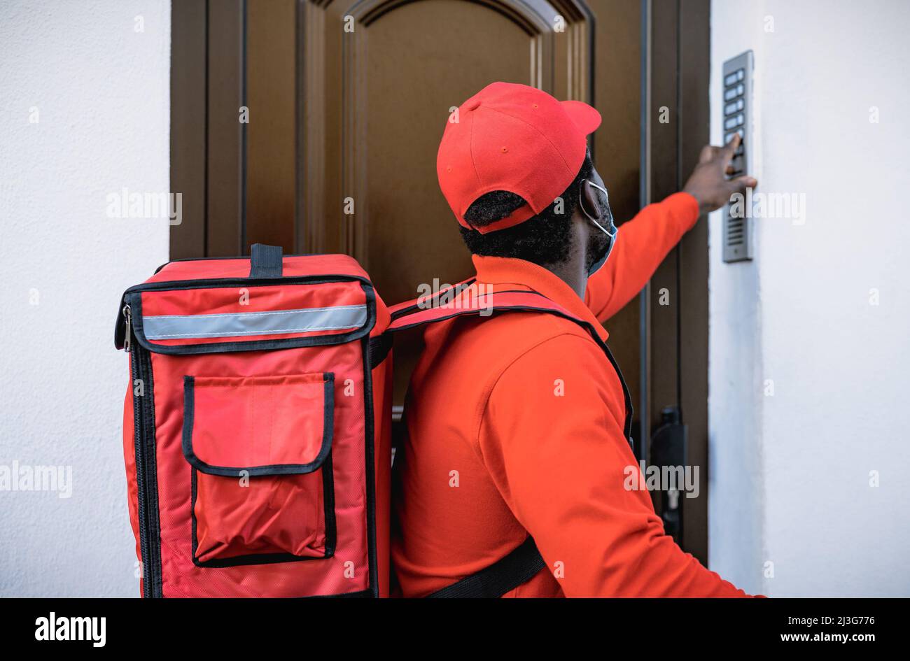 African rider man delivering meal to customers home while wearing face mask during corona virus outbreak - Delivery food concept Stock Photo