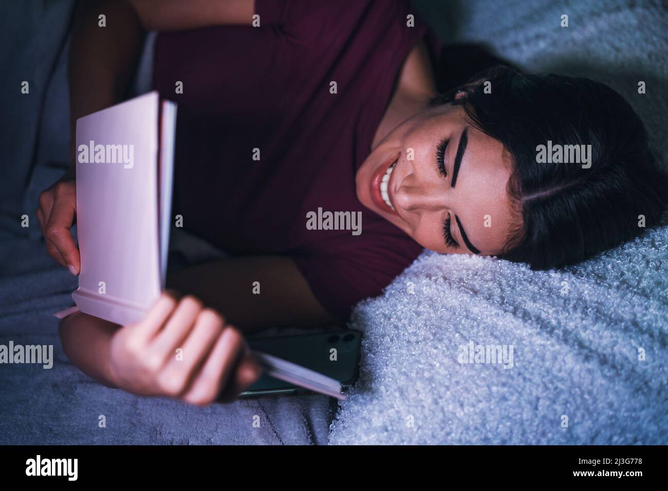 Young woman reading book in bed Stock Photo