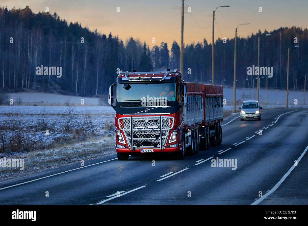 Red Volvo FH16 750 grain transport truck of K Halonen driving on highway 52 on a cold winter evening. Salo, Finland. December 22, 2021. Stock Photo
