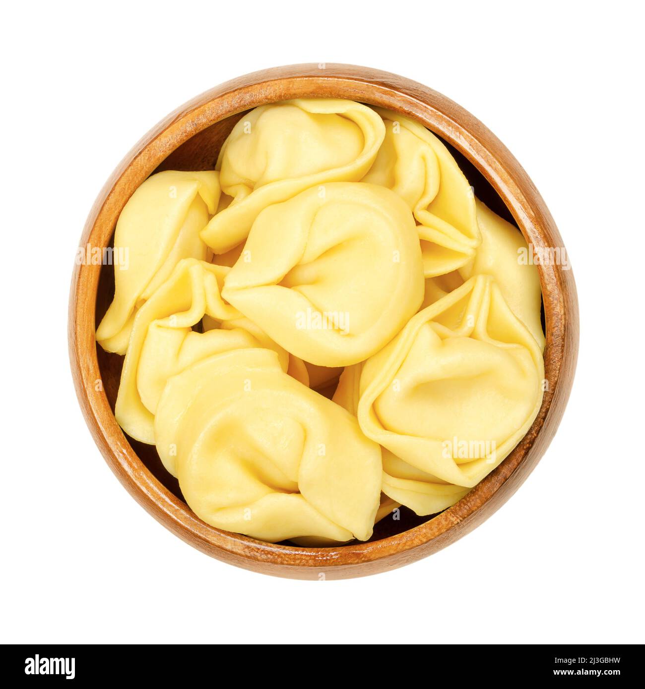 Raw tortelloni pasta in a wooden bowl. Ring-shaped stuffed Italian dumplings with same shape as tortellini, but larger. Stock Photo