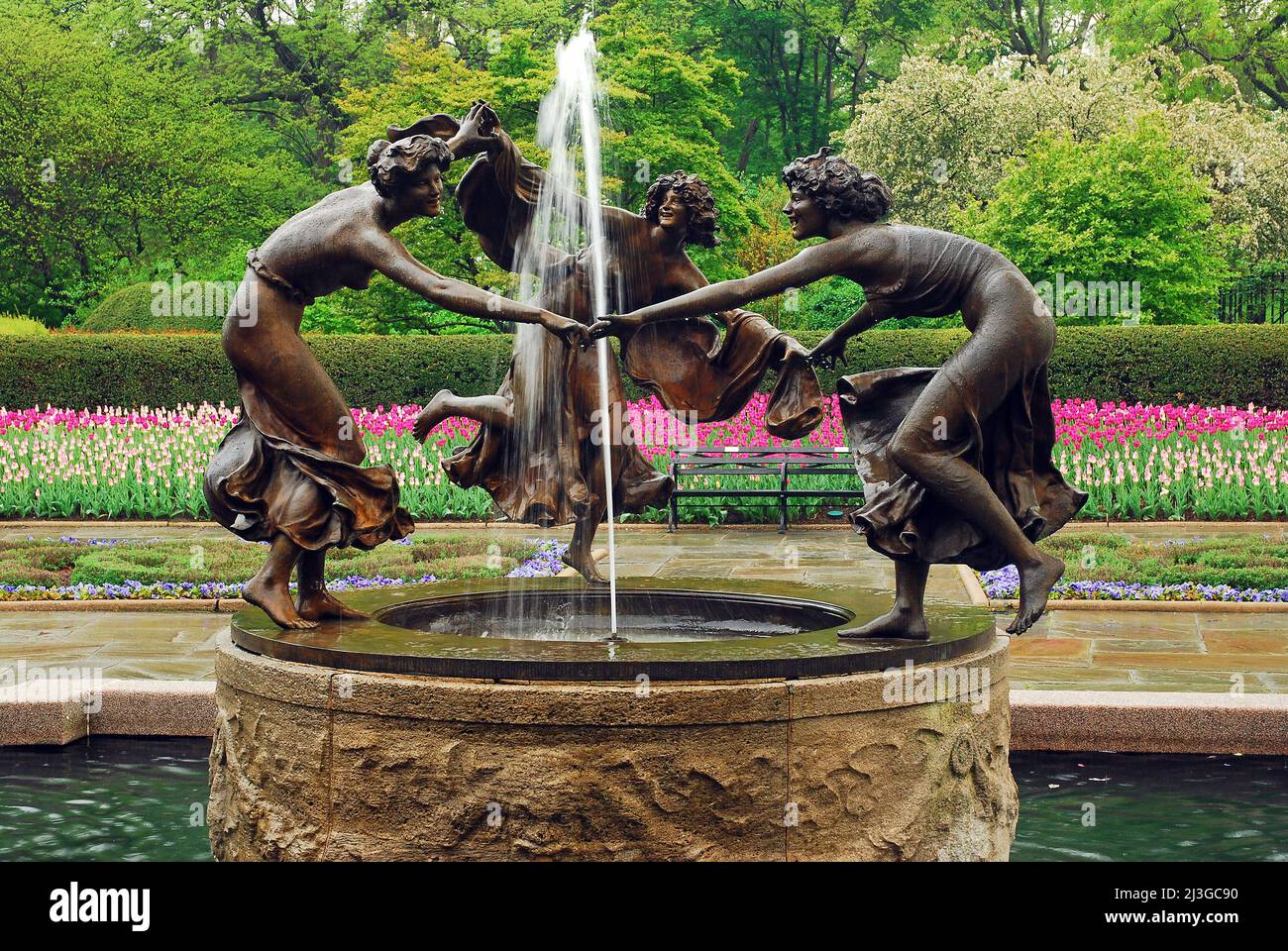 The sculpture of three dancing nymphs circling a water fountain highlights the Conservatory Gardens of New York's Central Park in spring Stock Photo