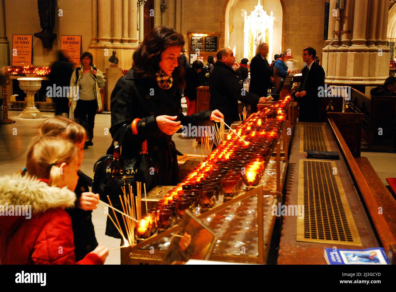 A mother and her daughters light prayer candles at St Patrick's Cathedral in New York City Stock Photo