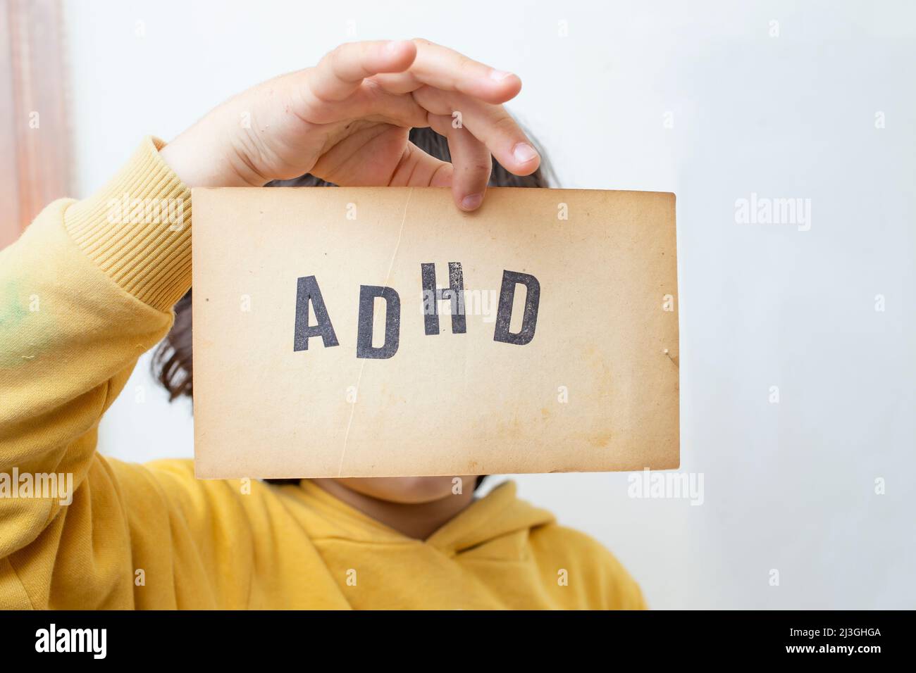 Child's hand, holding a vintage paper page with the abbreviation ADHD written on it Stock Photo