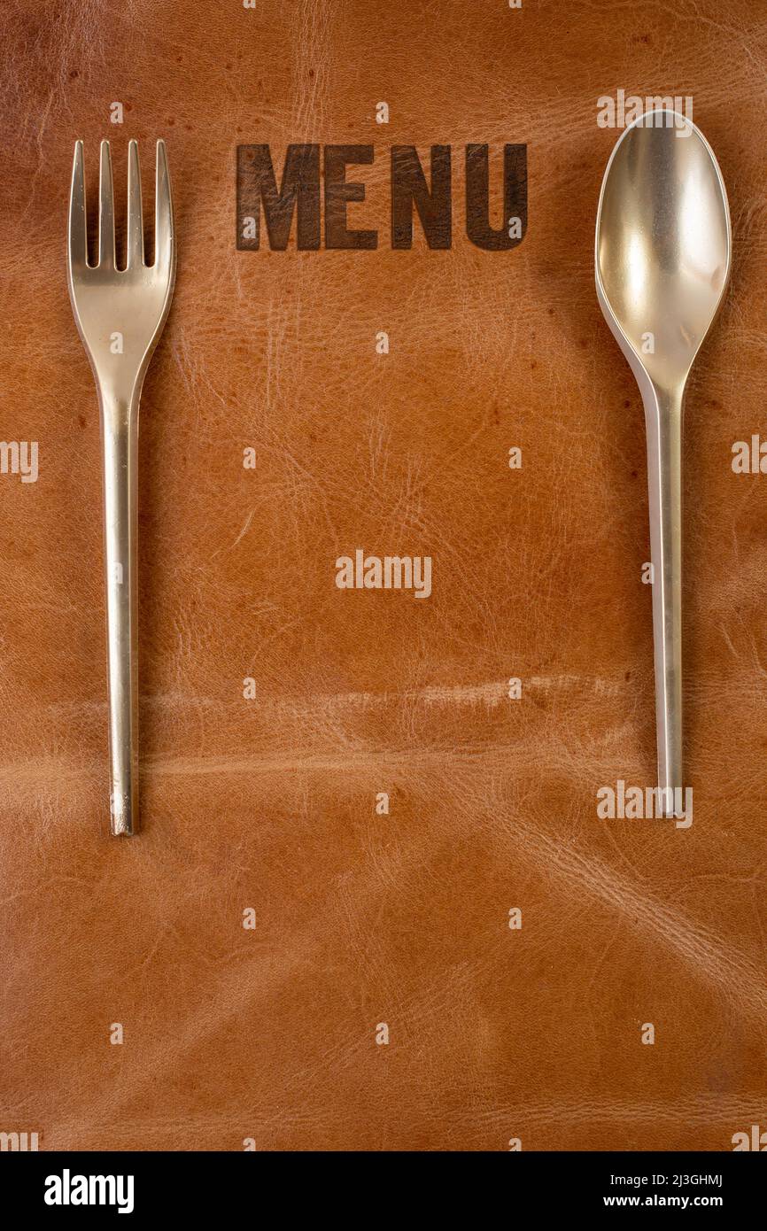 Menu written on brown leather with golden spoon and fork. Restaurant