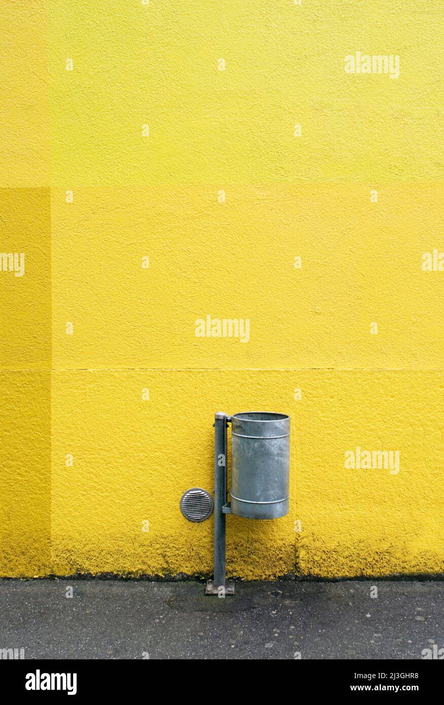 rubbish bin against yellow wall Stock Photo
