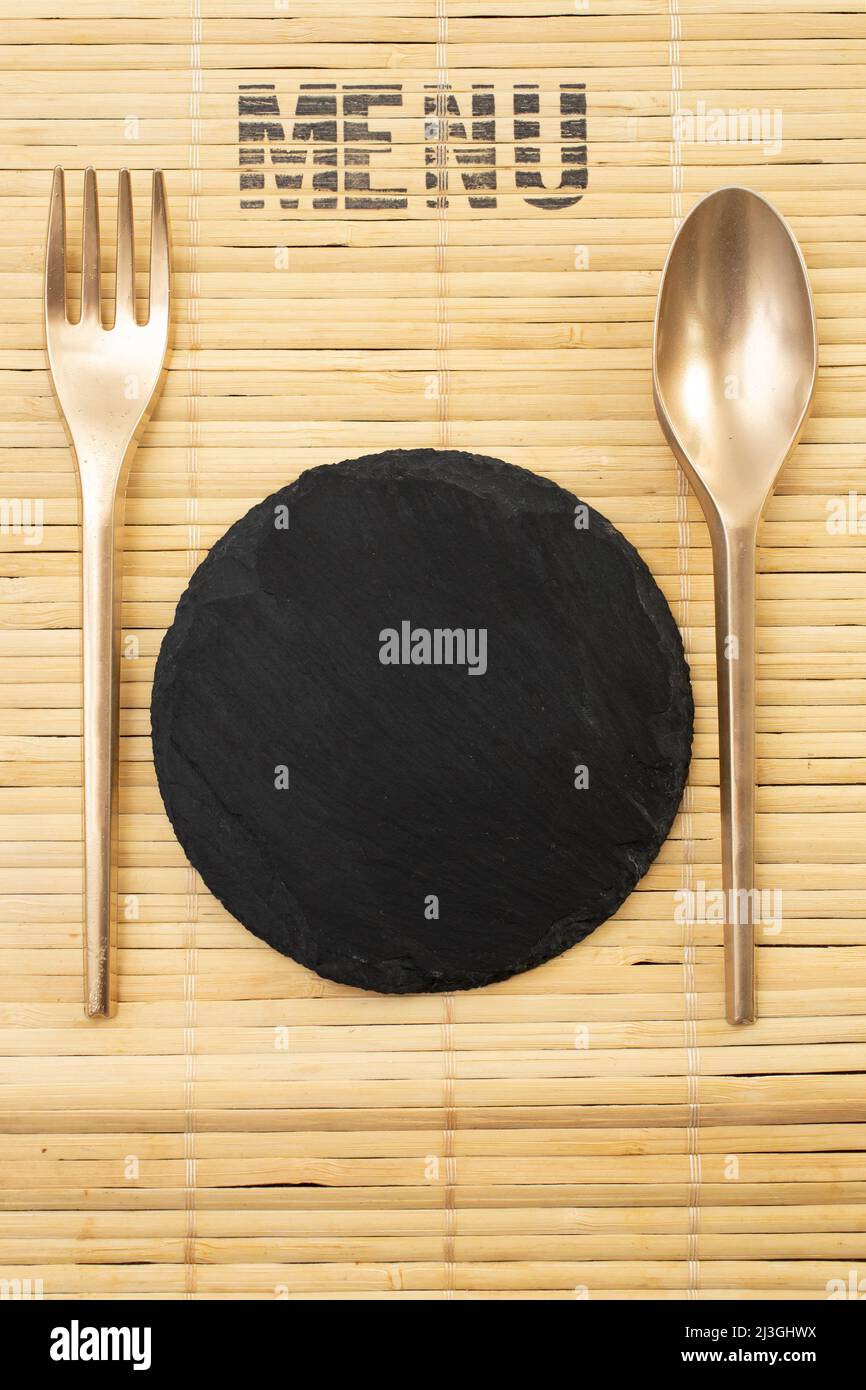 Menu cover mockup with a bamboo place mat, golden painted cutlery and