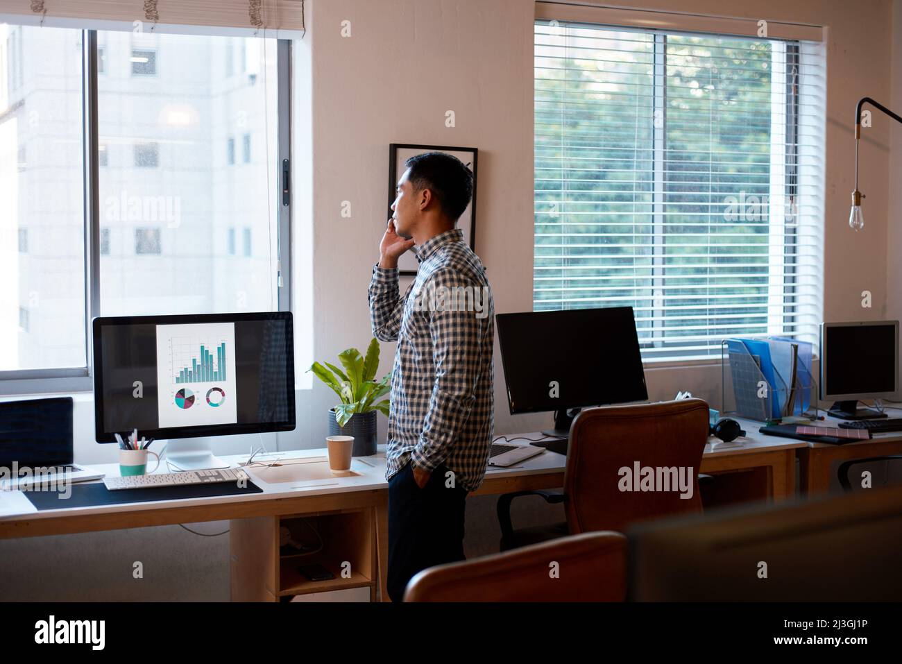 A wide shot of a businessman in an empty office on a phonecall Stock Photo