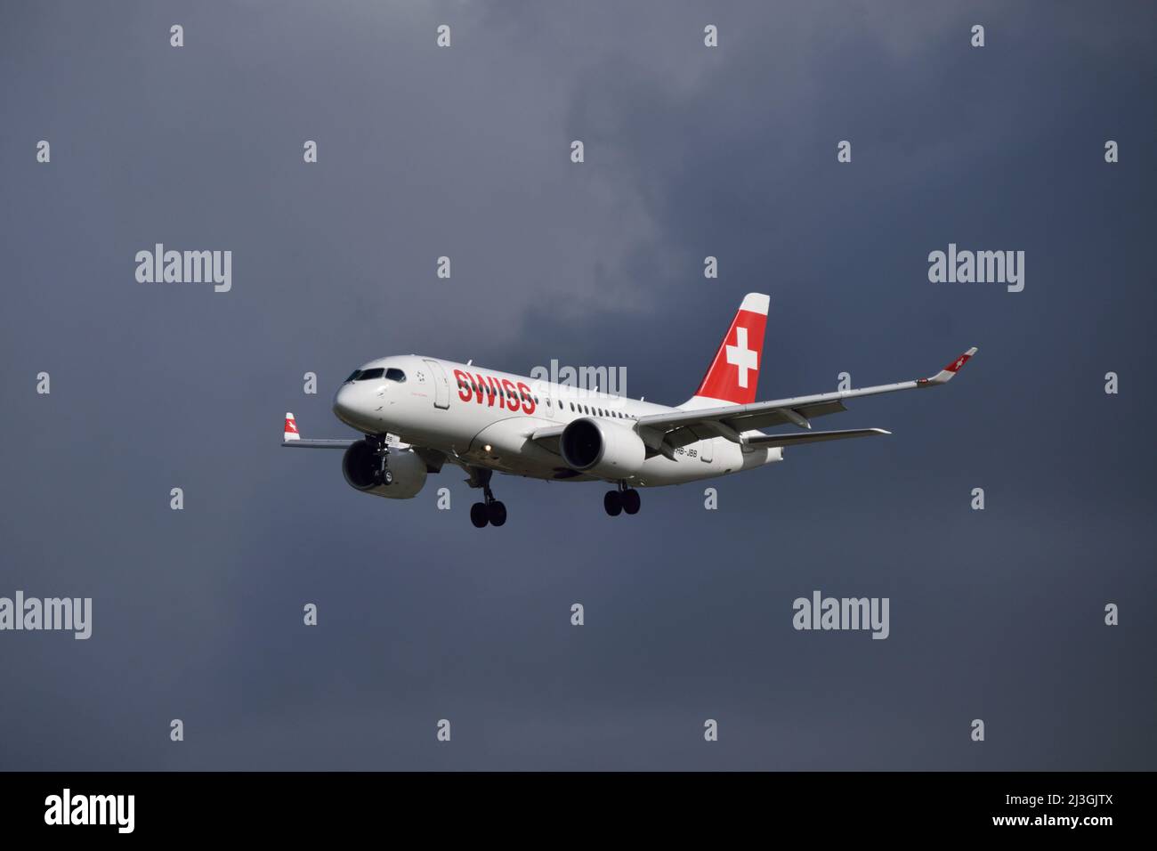Swiss Airlines Airbus A220 coming in to land at London City Airport on a stormy day Stock Photo