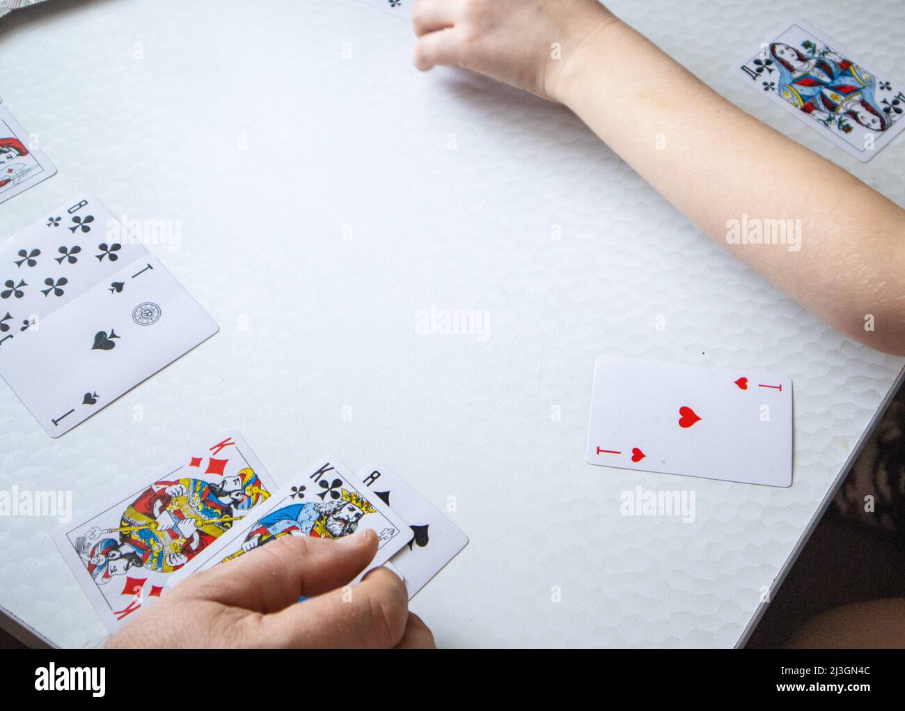 Closeup of a man's hand and a child's hand laying out playing cards on