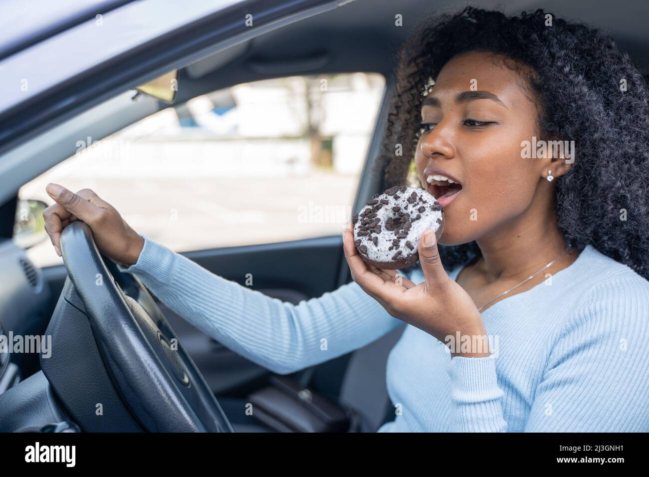 One black woman smiling eating a doughnut Stock Photo