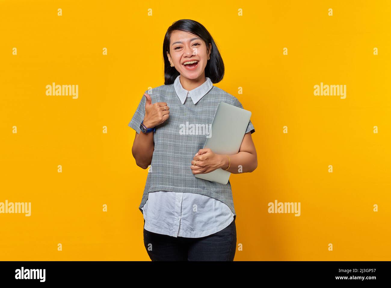 Cheerful beautiful Asian woman holding laptop and showing thumbs up ...