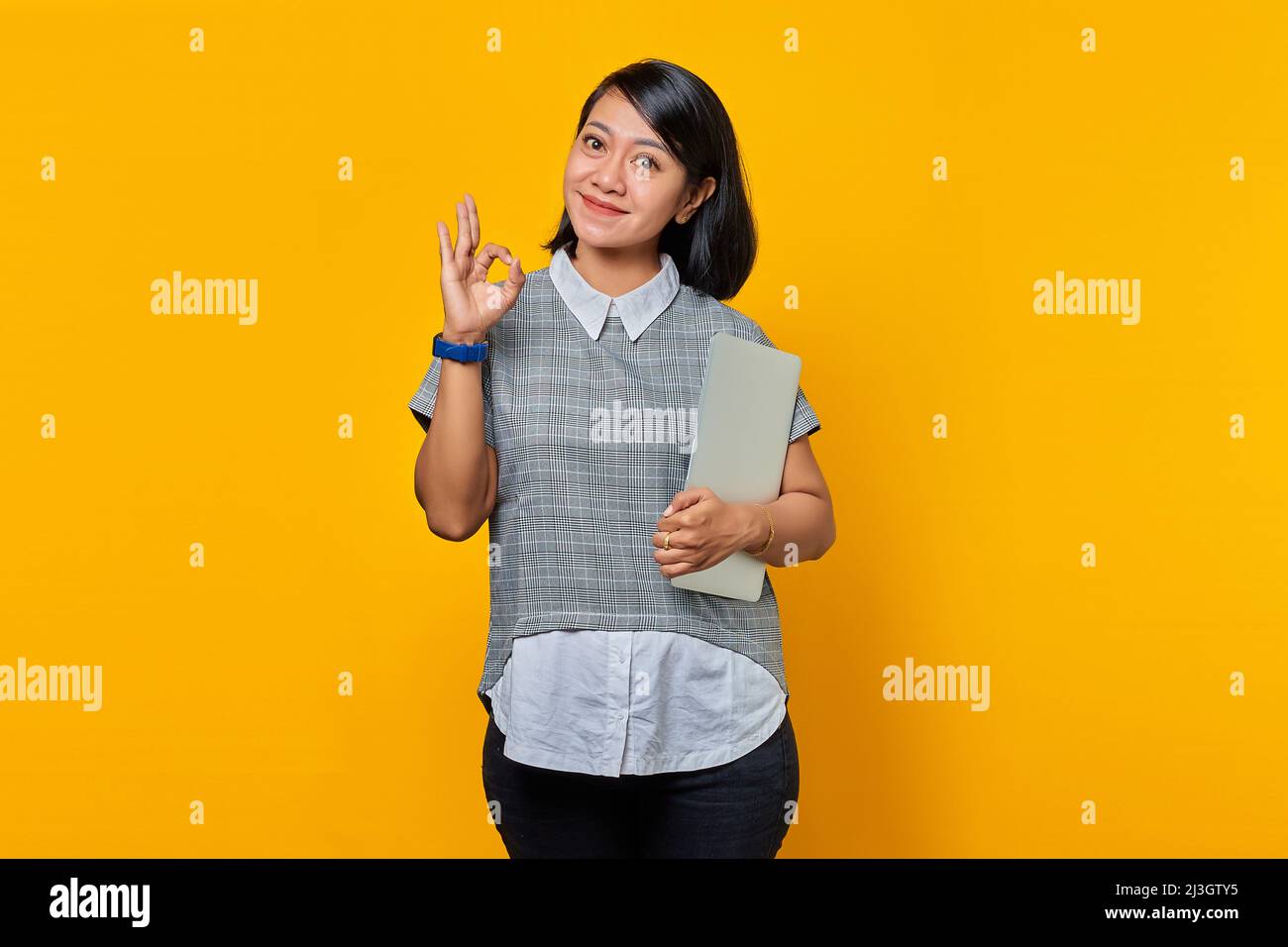 Beautiful Asian woman holding laptop smiling and showing okay sign over ...