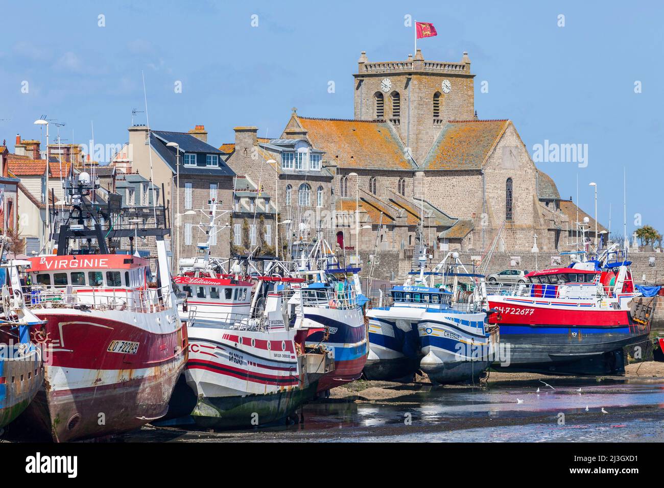 France, Manche, Cotentin, Barfleur, labeled The Most Beautiful Villages of France, fishing and beaching harbour at low tide, trawler fishing boats and Saint-Nicolas church with flag of Normandy Stock Photo