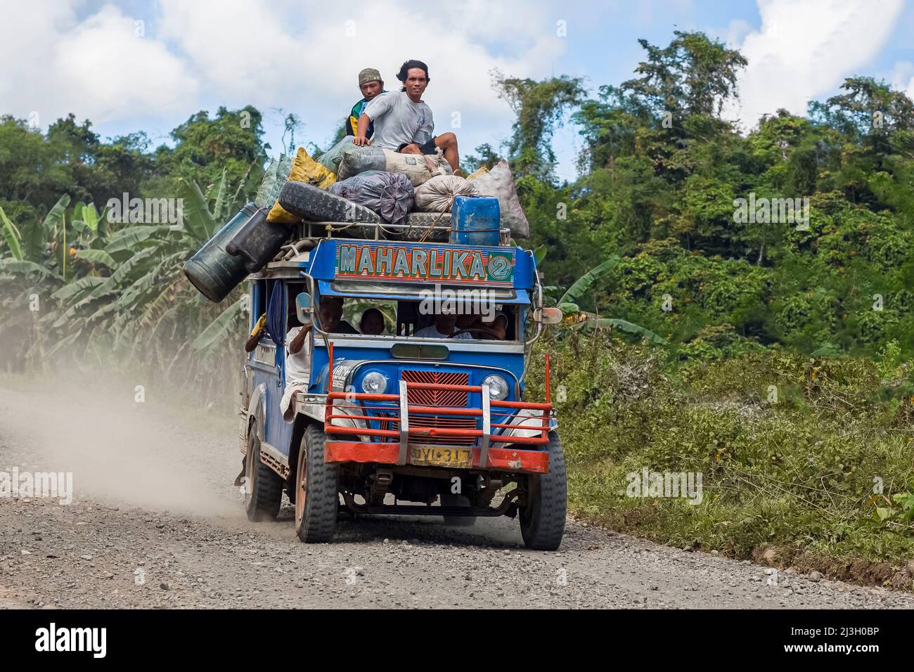 Philippines, Palawan, Quezon, Punta Baja Road, two filipino men travel on the roof of a jeepney going at full speed on a gravel road Stock Photo