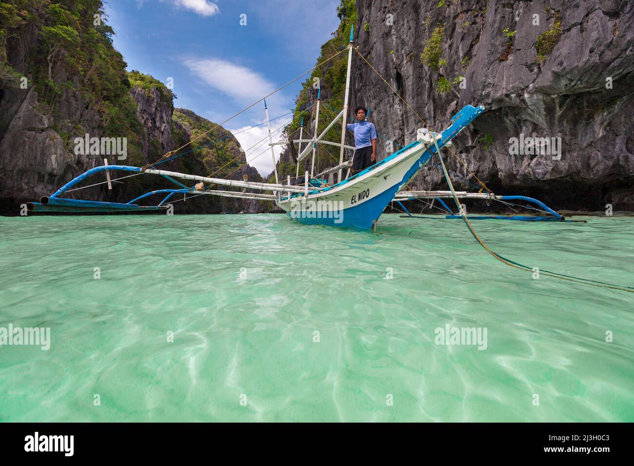 Philippines, Palawan, El Nido, Bacuit Archipelago, Miniloc Island, an outrigger canoe bearing the name El Nido comes out of Big Lagoon, on turquoise water Stock Photo