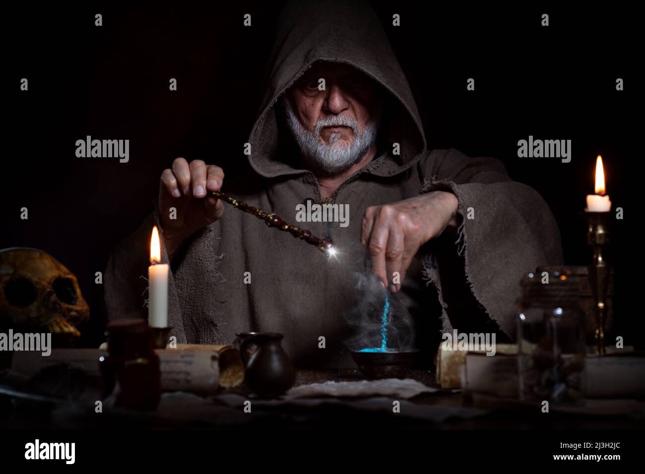Old wizard conjures up elixir with magic wand Stock Photo