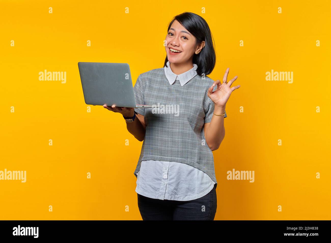 Beautiful Asian woman holding laptop smiling and showing okay sign over ...