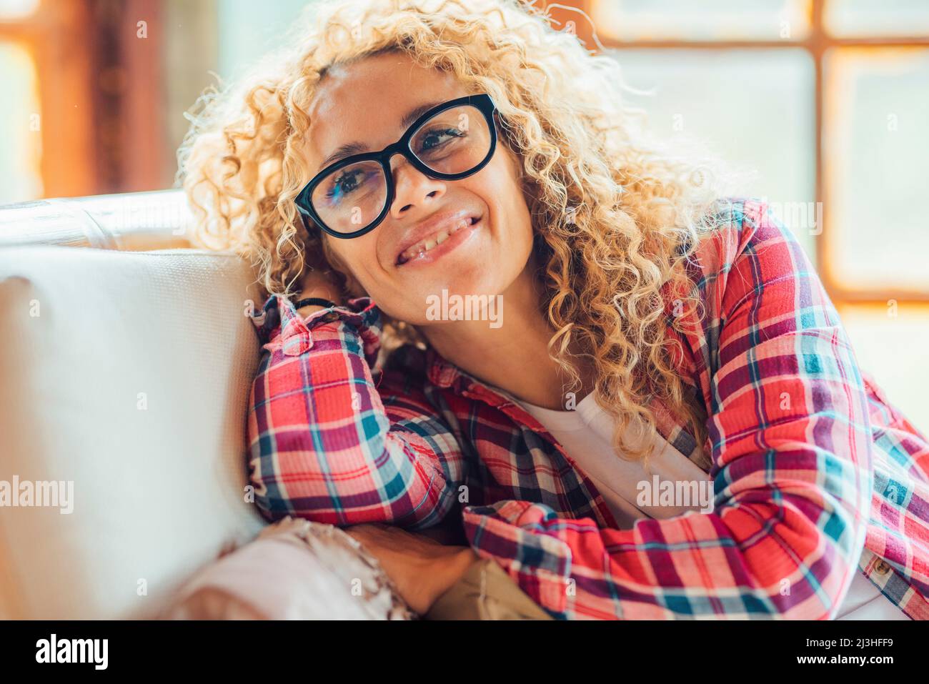 Woman, blonde, curls, check shirt, armchair, comfortable, sitting, smile, portrait, Stock Photo