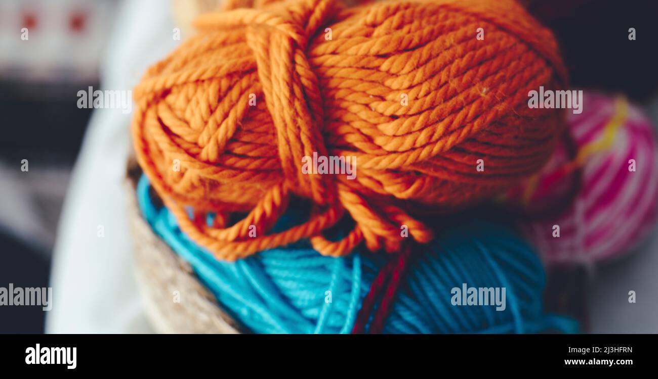 Close up of orange and blue yarn ball to do knit work hobby. Natural wool marino or alpaca high quality to make winter clothes and stylish clothing Stock Photo