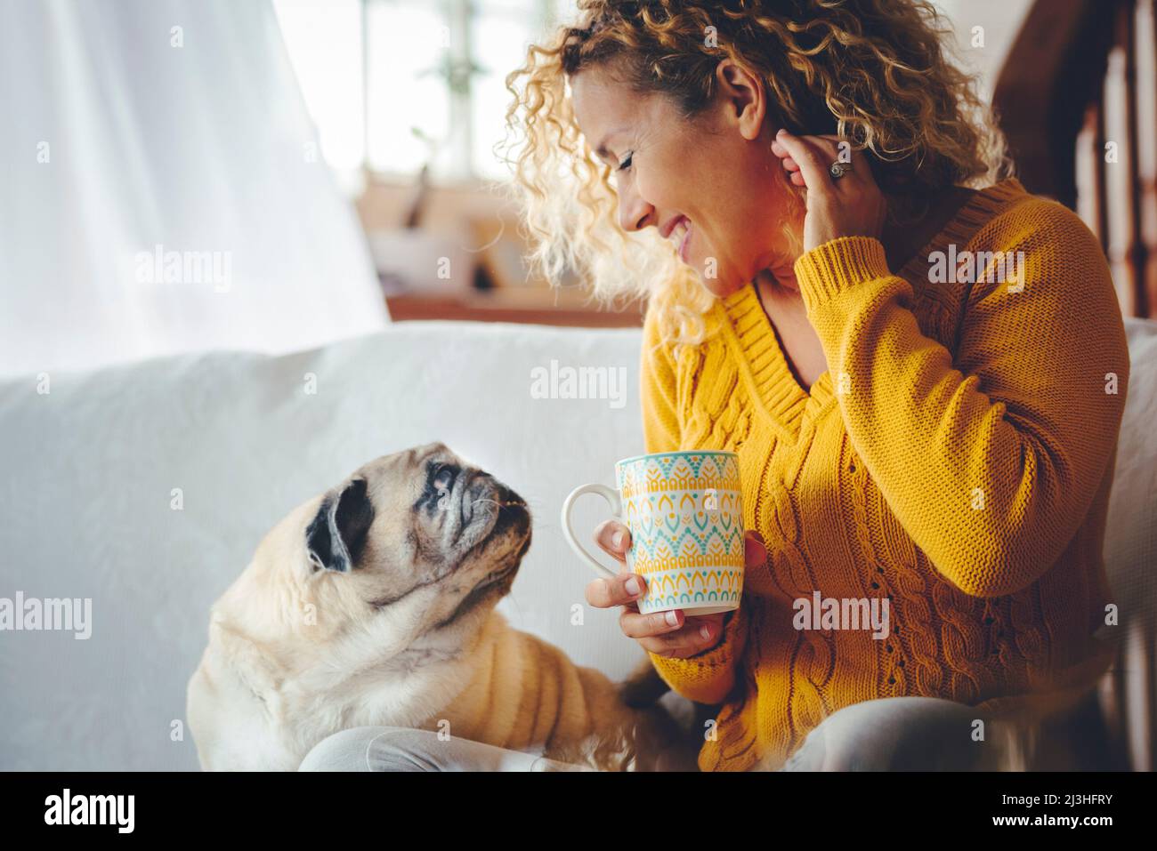 Woman with coffee mug and dog at home on sofa, smile, enjoy, happy, leisure, lifestyle, joy Stock Photo