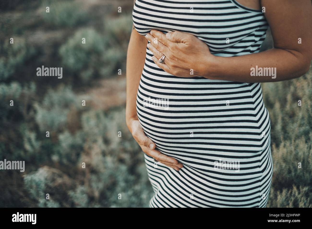 Close up of pregnant people. Mature lady 45 years old with pregnant belly in outdoor portrait. Future mommy newborn lifestyle. Adult woman waiting children. Stock Photo