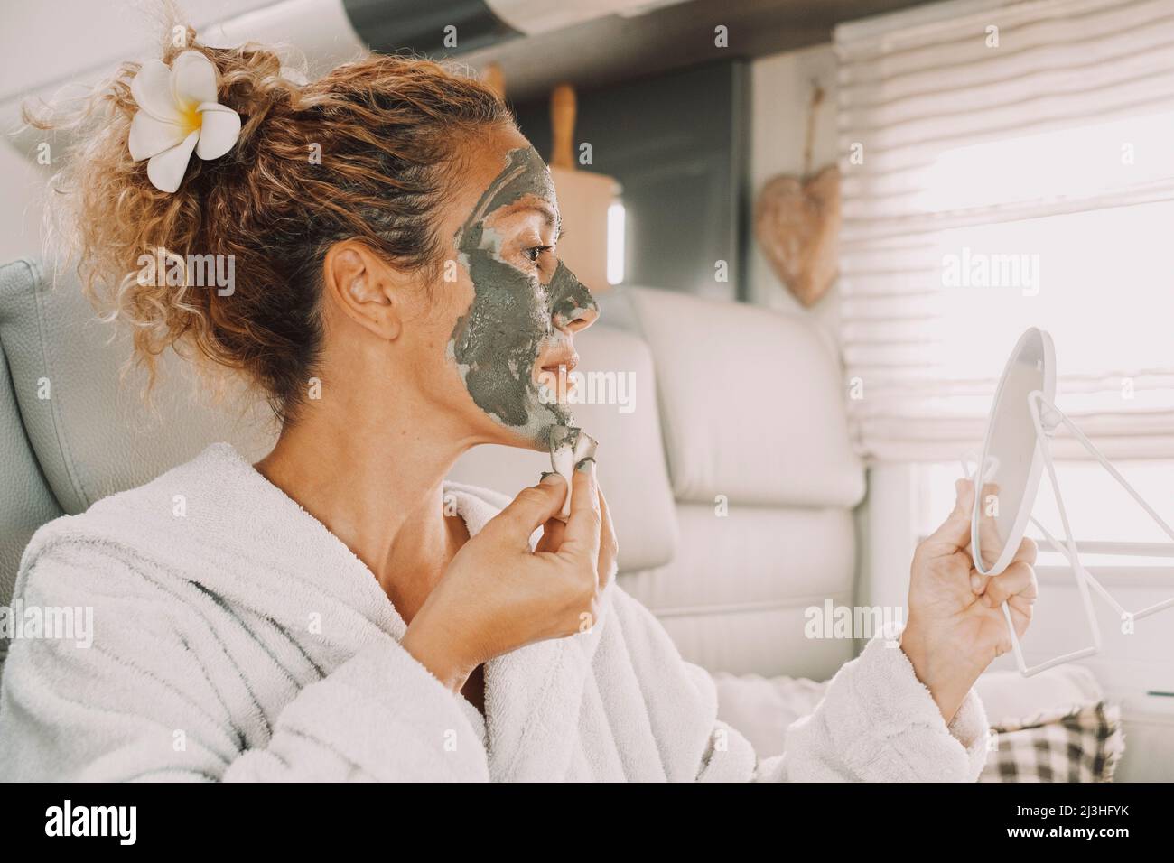 Woman applying face mask, anti-ageing skin treatment, mirror, care, beauty, lifestyle, close up, portrait, sideways Stock Photo