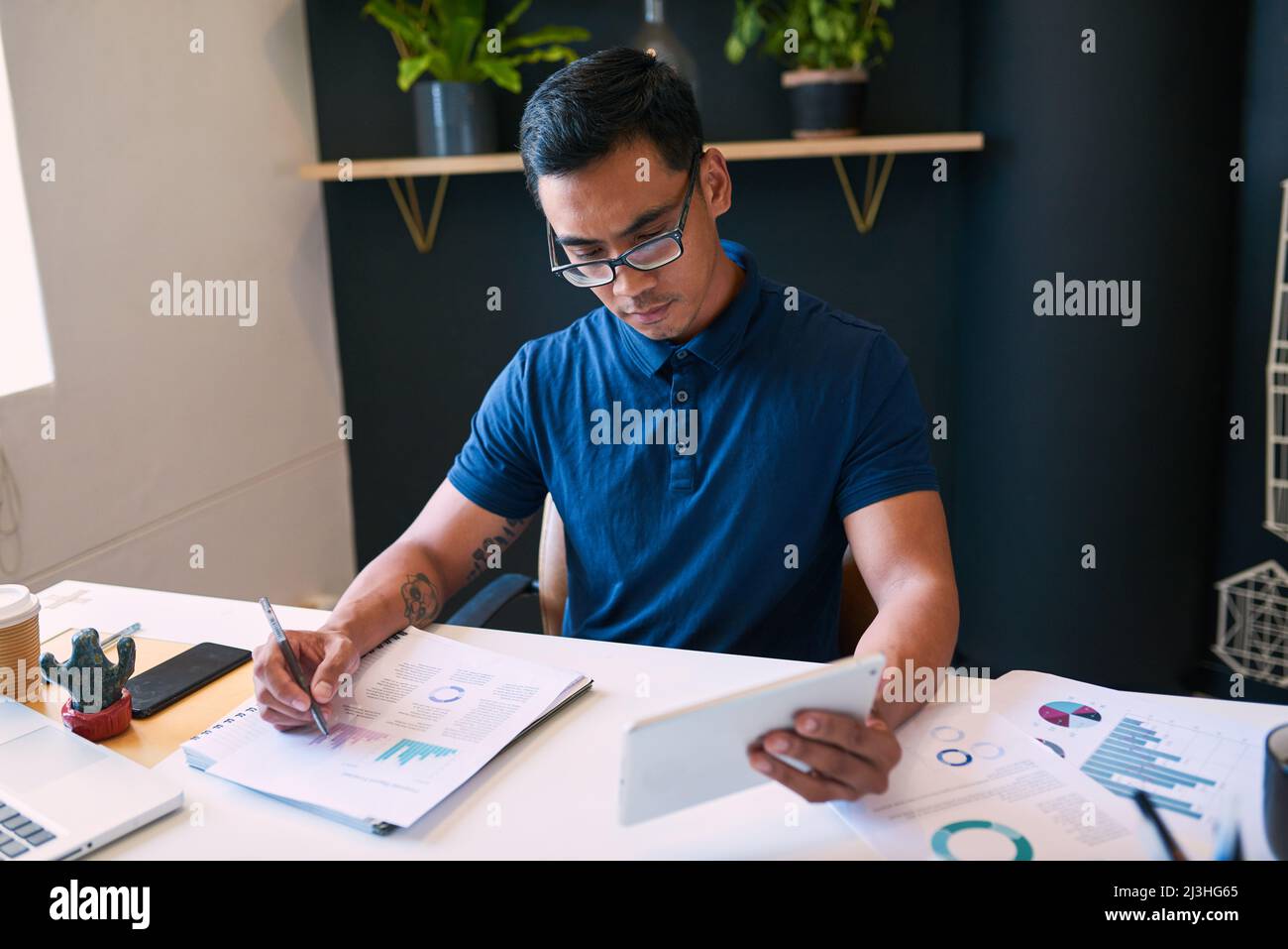 A businessman tracks data with graphs and analyses looking at his digital tablet Stock Photo