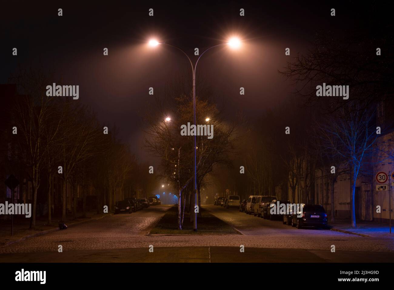 Germany, Luckenwalde, a little high fog at night under the street lamps Stock Photo