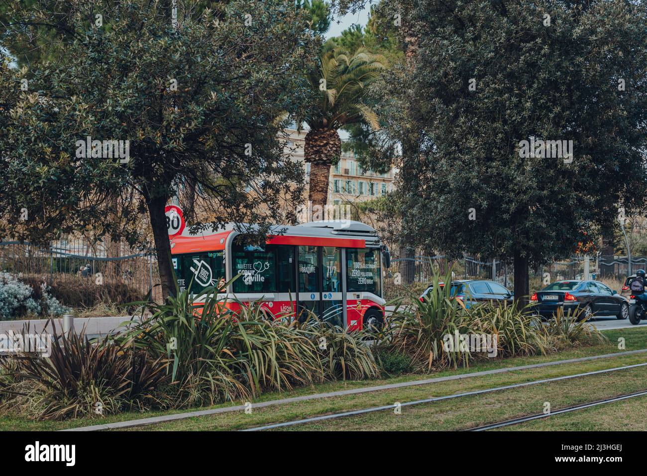 Nice, France - March 10, 2022: View through trees of free electric shuttle bus Coeur de Ville Navette (Heart of the City) on a street in Nice, a famou Stock Photo