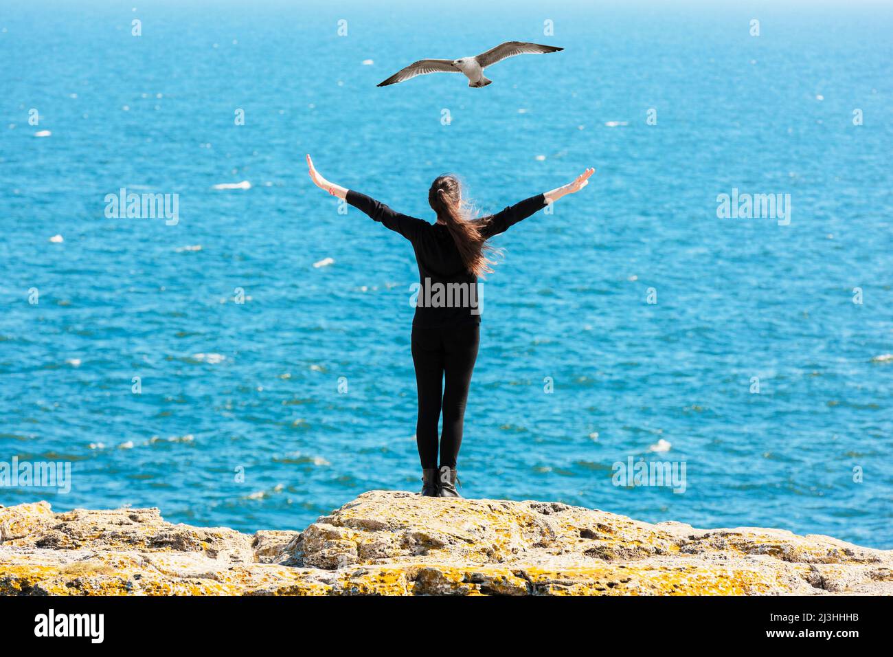 Woman with outstretched arms on a cliff Stock Photo