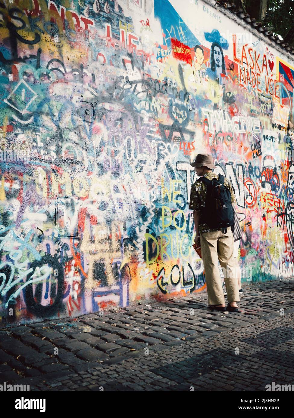 man standing in front of a graffiti wall in Prague (John Lennon Wall) Stock Photo