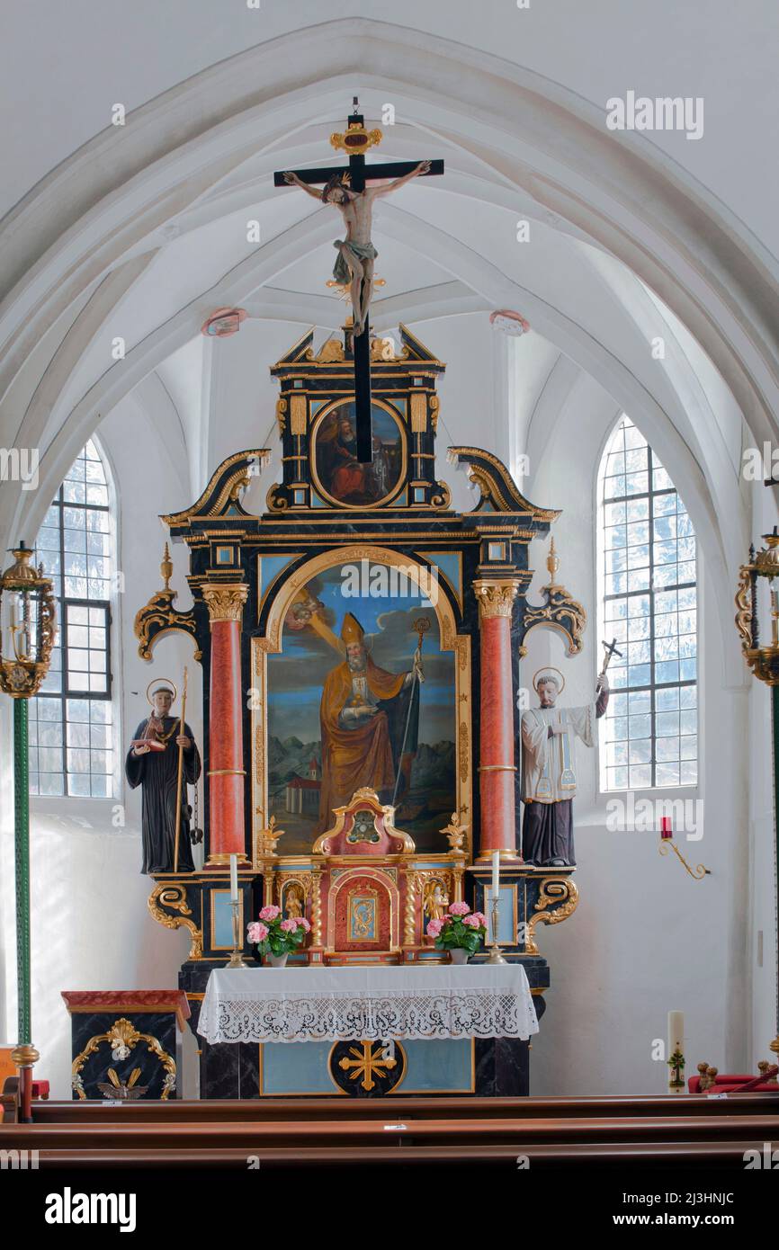 The two-columned high altar dates from 1672 with an altar leaf showing St. Nicholas as patron of the rafters in front of an evening scene. As assistant figures are the saints Leonhard and Blasius. Catholic cemetery church of St. Nicholas in Mittenwald, Upper Bavaria Stock Photo