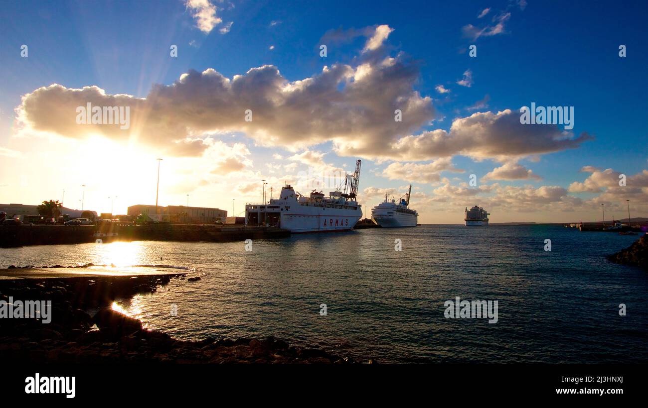 Spain, Canary Islands, Fuerteventura, capital, Puerto del Rosario, view of the harbor, backlight, sun behind clouds, ferry and two cruise ships, water dark, sky blue, clouds gray-white Stock Photo