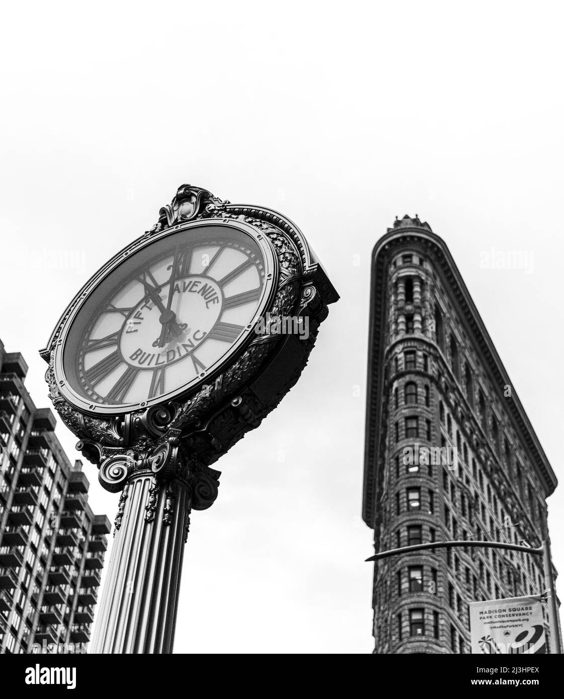 23 Street, New York City, NY, USA, Historic Flatiron or Fuller Building, a 22 Story triangular shaped steel framed Landmark, built in 1902 and considered as one of the first skyscrapers ever built and one of New York's famous sidewalk clocks Stock Photo