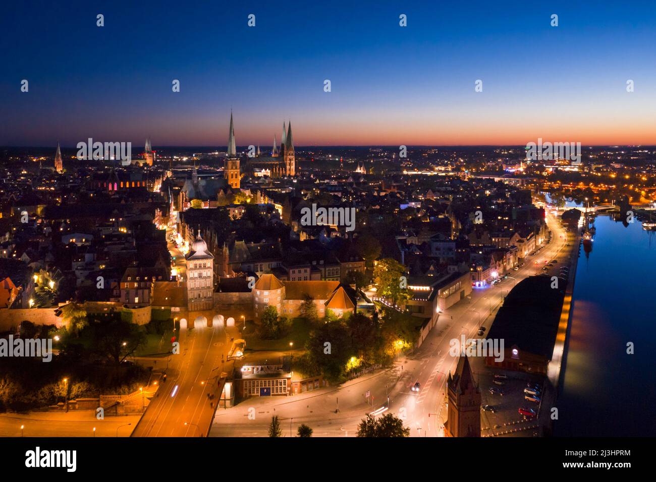 Aerial view over the Burgtor, river Trave and old town and churches of the Hanseatic City of Lübeck at night, Schleswig-Holstein, Germany Stock Photo
