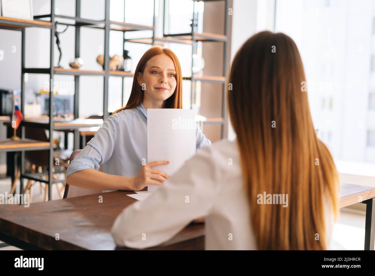 Rear view of unrecognizable young woman employers being interviewed for job in design company. Stock Photo