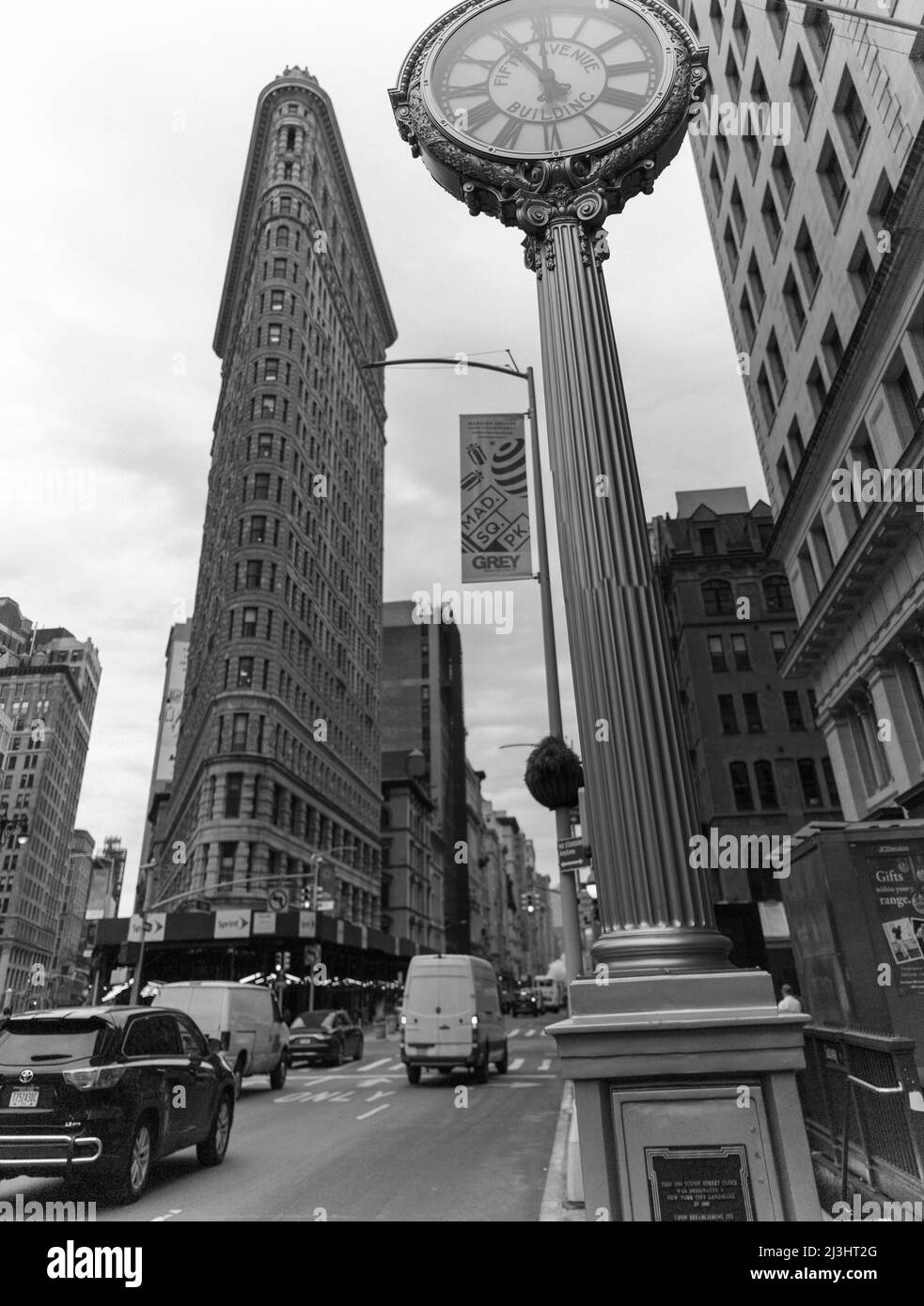 23 Street, New York City, NY, USA, Historic Flatiron or Fuller Building, a 22 Story triangular shaped steel framed Landmark, built in 1902 and considered as one of the first skyscrapers ever built and one of New York's famous sidewalk clocks Stock Photo