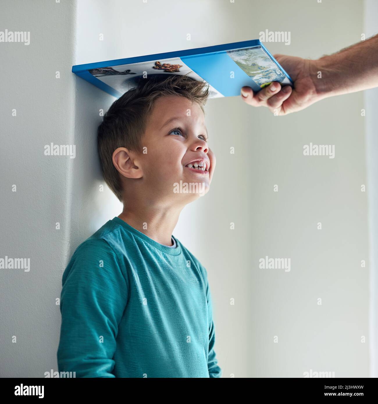 https://c8.alamy.com/comp/2J3HWXW/hes-getting-taller-and-taller-by-the-day-cropped-shot-of-a-little-boy-getting-his-height-measured-against-a-wall-with-a-book-2J3HWXW.jpg