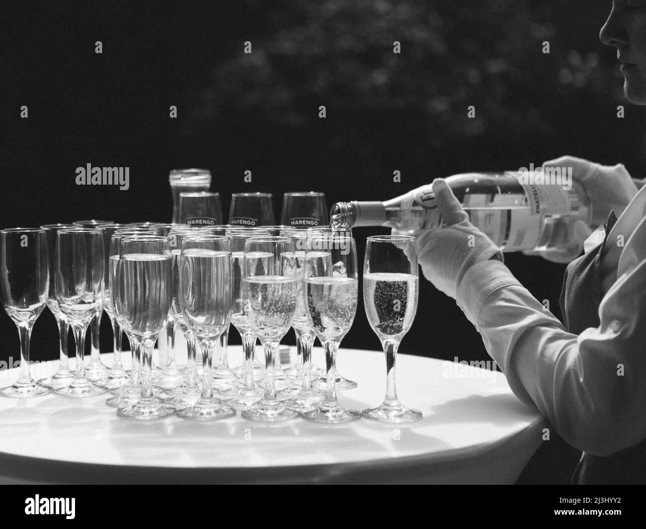 pouring champagne for a toast in a celebratory atmosphere with glasses of champagne on golden flakes bokeh grain effect Stock Photo