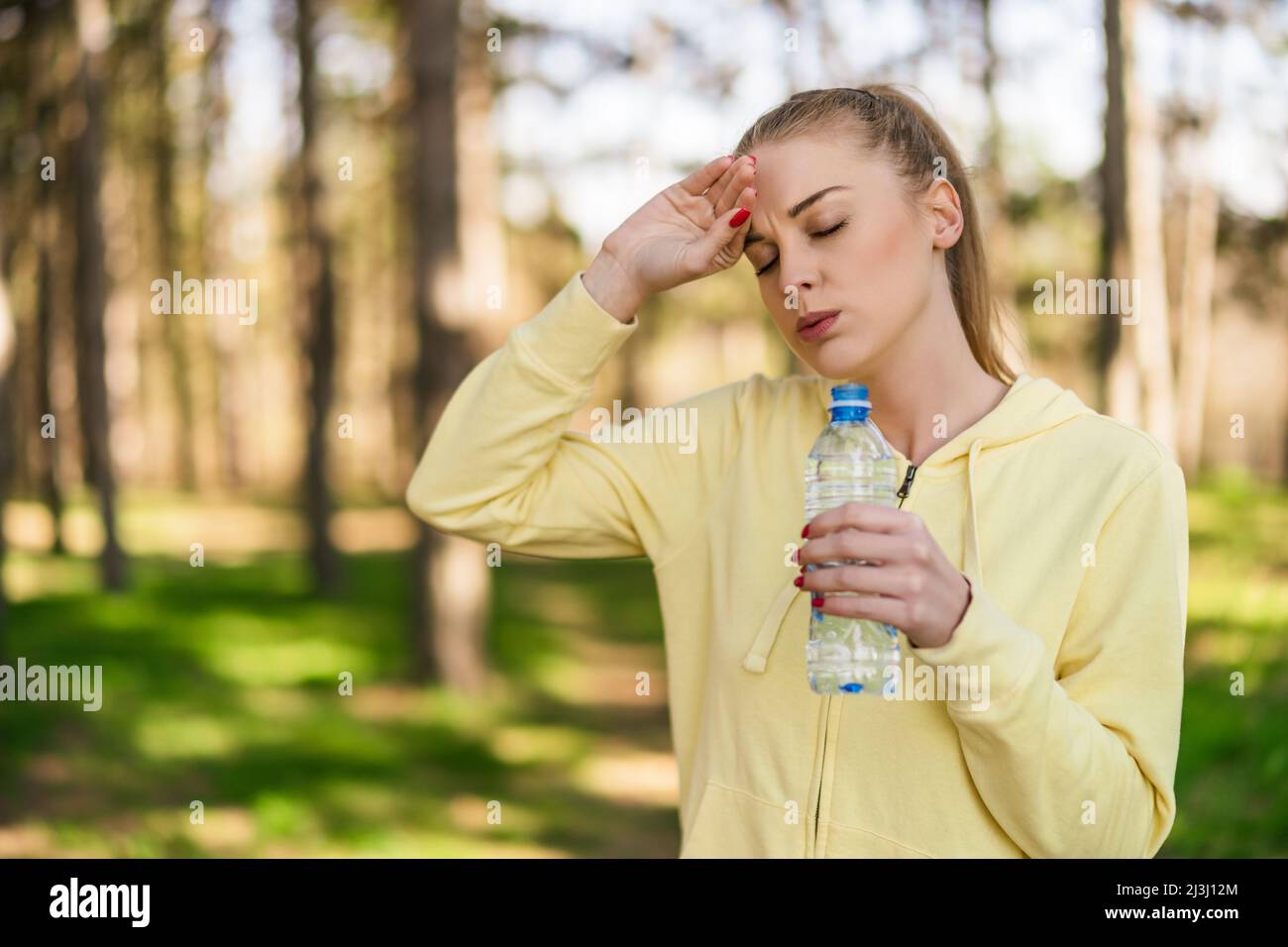 Tired woman drinking water after exercise in the nature Stock Photo - Alamy, image size:1300x956