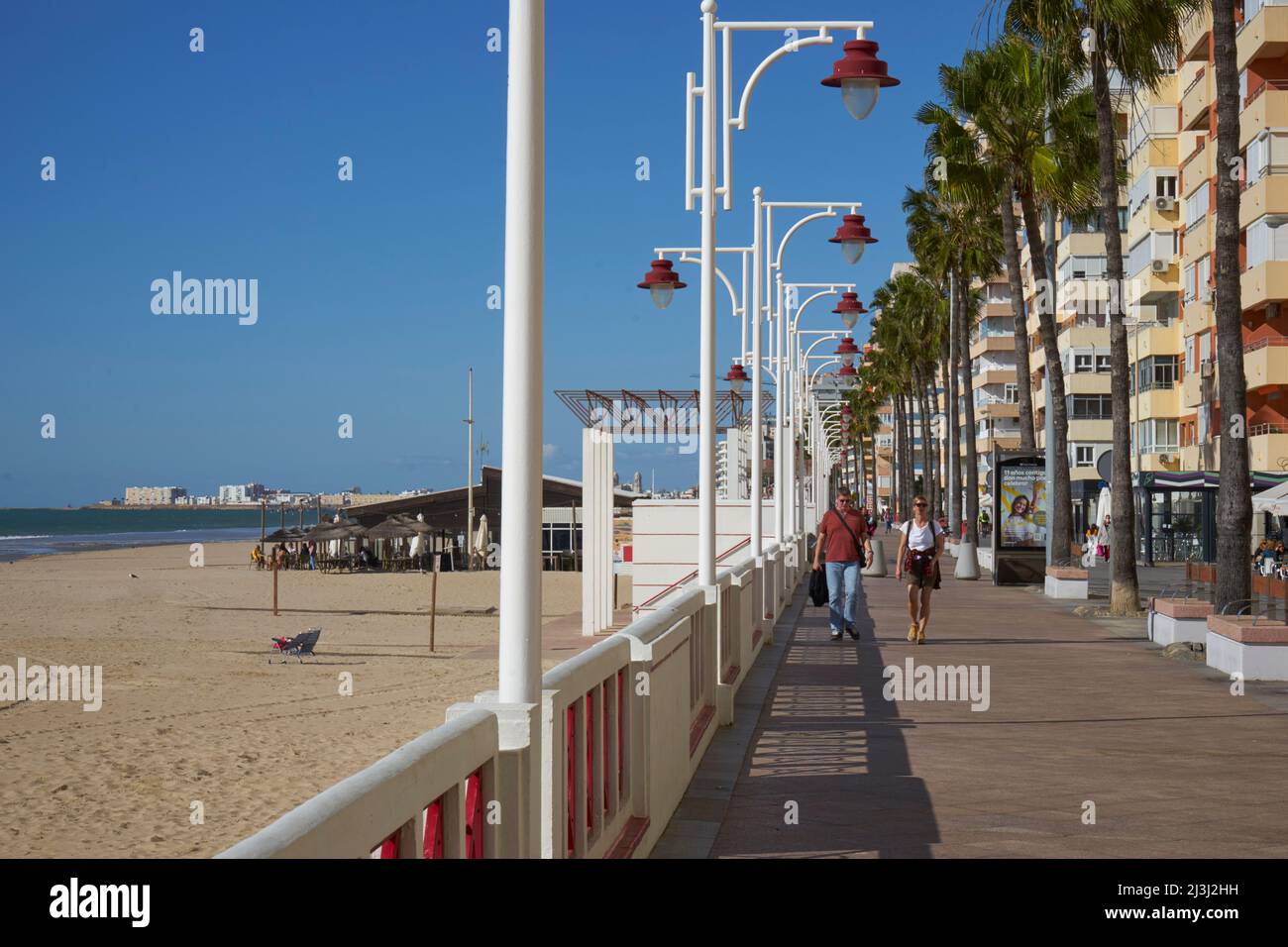 Beach front promenade with couple and palm trees, east Cadiz, Spain Stock Photo