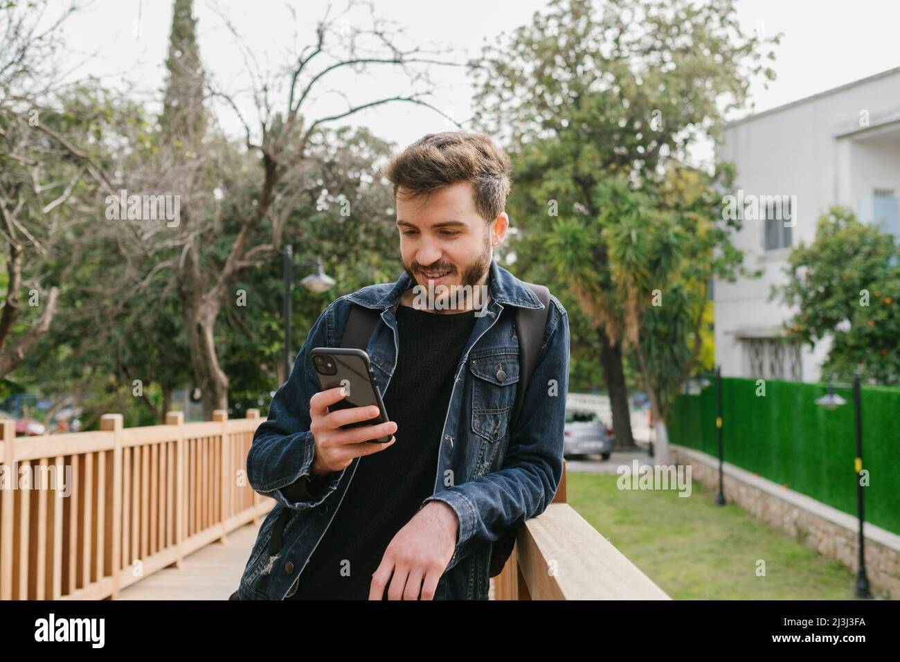 Happy young man on the handsome adult reading tech articles, man in denim jacket