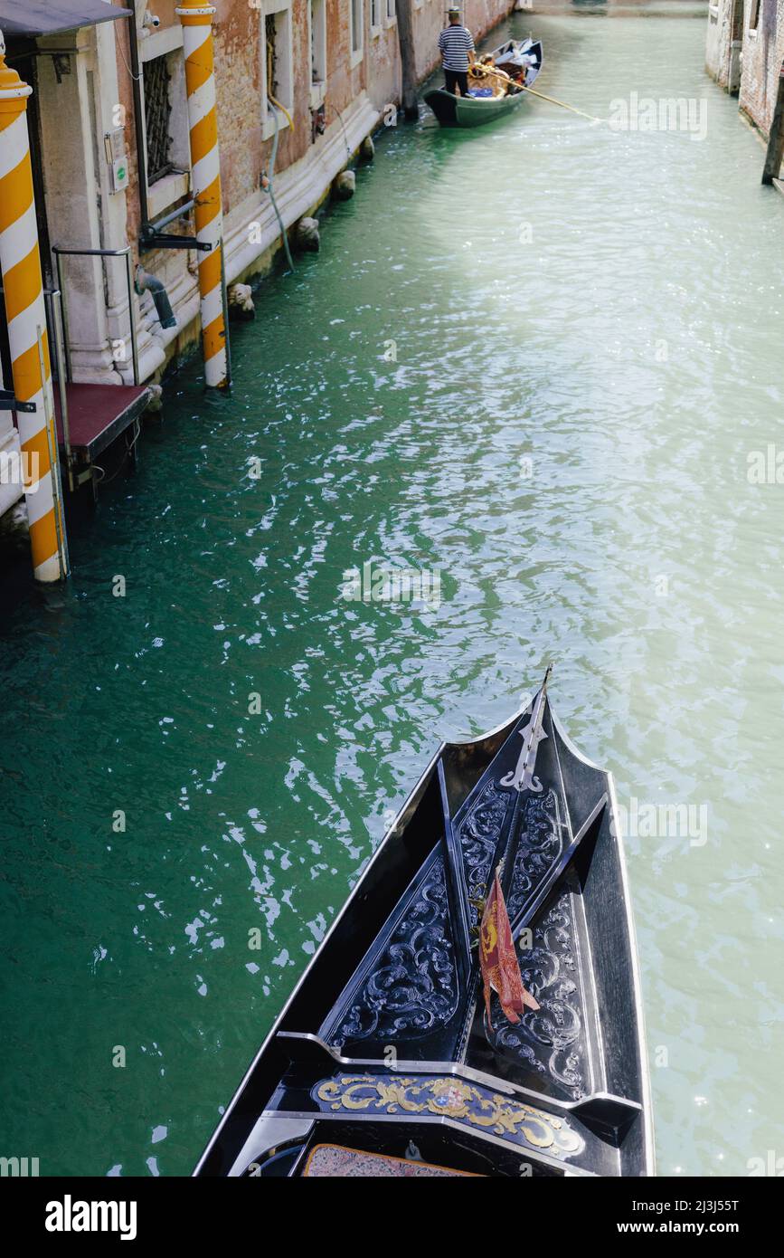 View of the top of a Venetian gondola underway on a narrow canal in Venice, Italy Stock Photo