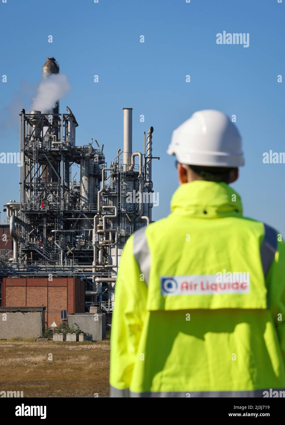 Oberhausen, North Rhine-Westphalia, Germany - Air Liquide, hydrogen production in the chemical park OQ Chemicals. Air Liquid employee with company logo on yellow jacket in front of POX (partial oxidation) plant for conventional production of hydrogen and synthesis gas. Stock Photo