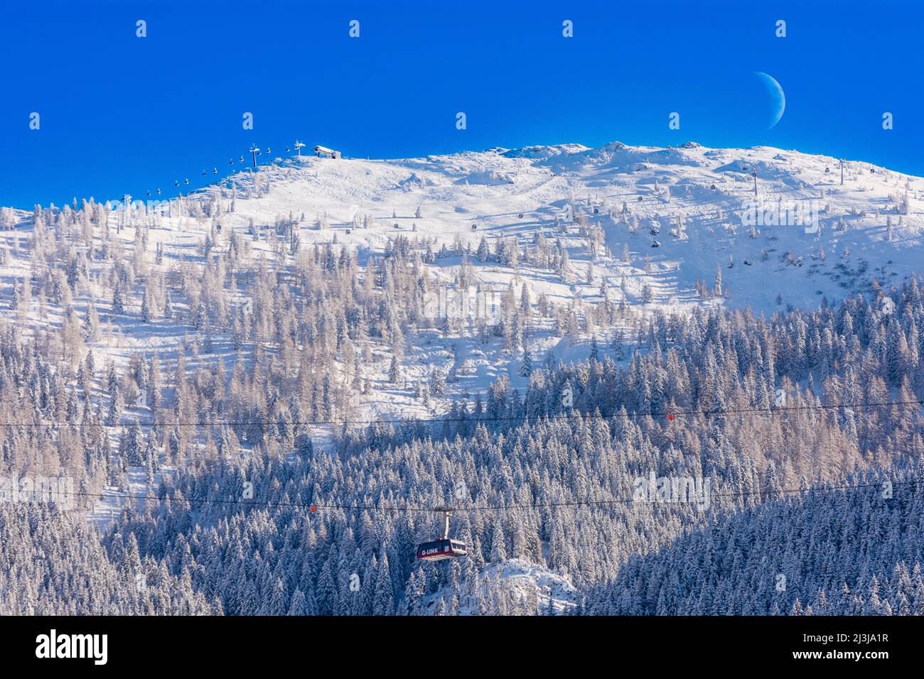 Wagrain, moon above summit Grießenkareck, car of G-Link aerial tramway, cable car ski area Snow Space Salzburg - Flachau, Wagrain, St. Johann-Alpendorf, ski ropeway, skilift, snow, forest in Pongau, Salzburg, Austria Stock Photo
