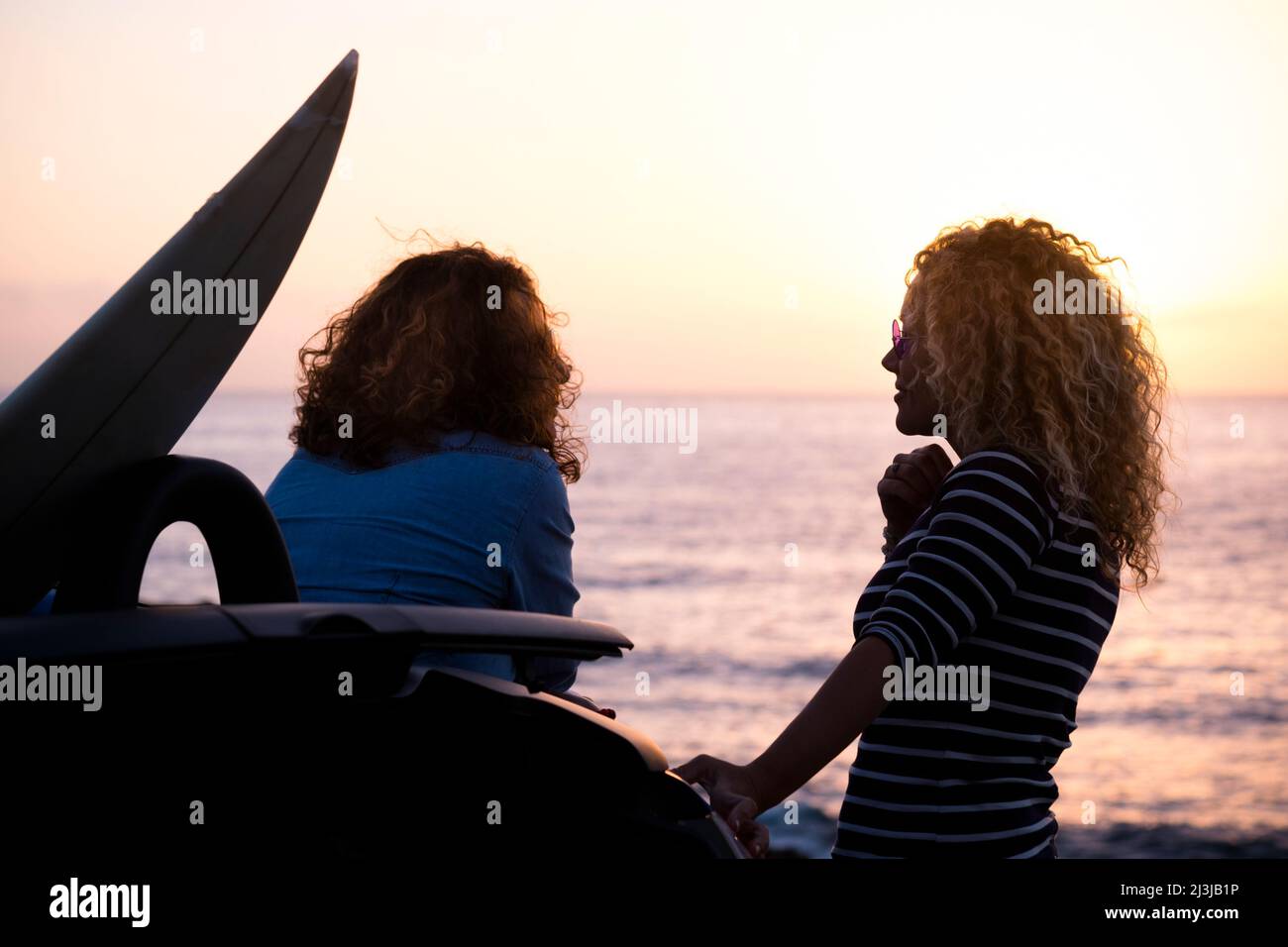 Couple of woman speaking outdoor. Travel and freedom happy lifestyle for female people. Beautiful sunset on the ocean. People enjoying leisure outdoor Stock Photo