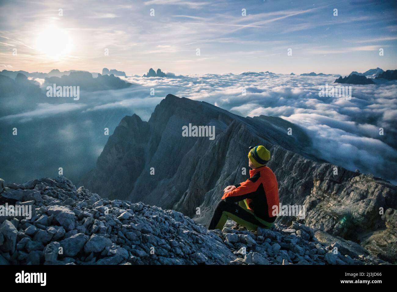 Europe, Italy, Alto Adige - Südtirol, Hiker looking at the landscape towards the Sexten Dolomites from the summit of the Picco di Vallandro / Dürrenstein illuminated by the light of the full moon Stock Photo